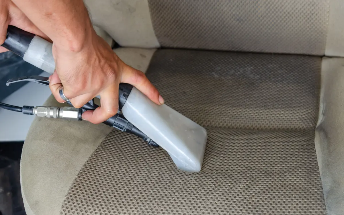An extractor nozzle cleaning a fabric car seat